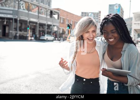 Laughing, happy and trendy students walking together in city after study class with a tablet downtown. Stylish, cool and funky women and young friends Stock Photo