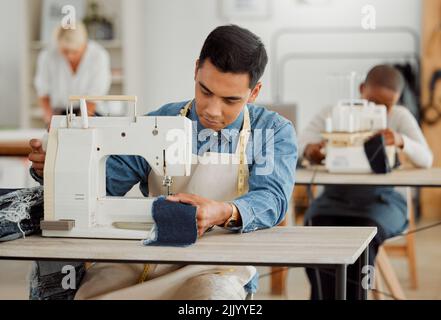 Creative fashion designer learning sewing skills on denim clothes in a clothing manufacturing factory. Young and fashionable student using a sewing Stock Photo
