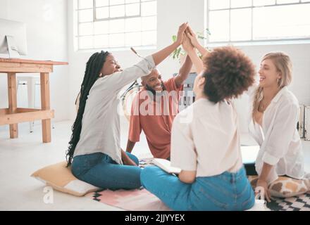 Happy, excited and successful creative team celebrating with a high five after finishing or completing a task. Fun, diverse group of business Stock Photo