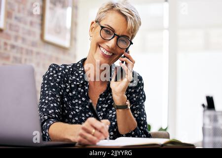 You have what it takes to make a success of anything. a mature woman making notes while talking on her cellphone. Stock Photo
