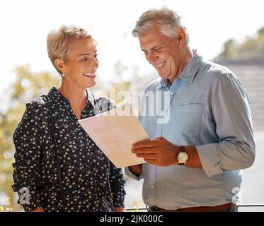 Heres the paperwork. a senior male realtor going through paperwork with a client. Stock Photo