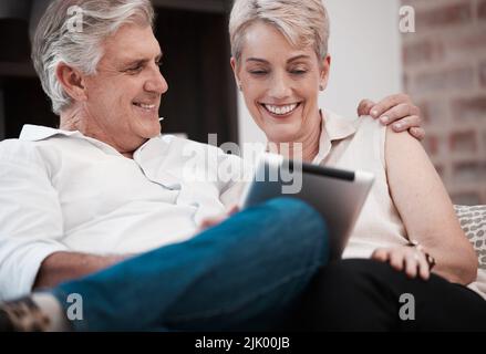 I gave her my heart every year since hello. a mature couple using a digital tablet at home on the sofa together. Stock Photo