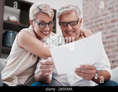 Heres to the second leg of forever. a mature couple going through paperwork on the sofa at home together. Stock Photo