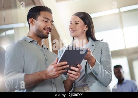 What do you think about my plan. two coworkers talking while using a digital tablet. Stock Photo