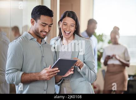 We should meet over coffee. two coworkers talking while using a digital tablet. Stock Photo