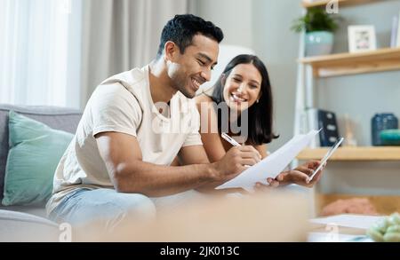 Were doing so well with our finances. a young couple sitting together in their living room at home and calculating their finances. Stock Photo