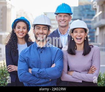 Were the best architects in the city. a diverse group of businesspeople standing together with their arms folded while wearing hardhats. Stock Photo