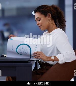 All of these reports keep her busy. a young businesswoman going through paperwork in an office at work. Stock Photo