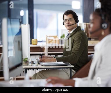 Hes got some work to do. two call center agents working in an office. Stock Photo