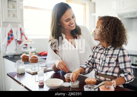 Believe you can fly. an adorable little girl baking with her mom at home. Stock Photo