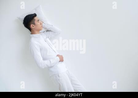 Young man in pajamas sleeping on white floor Stock Photo