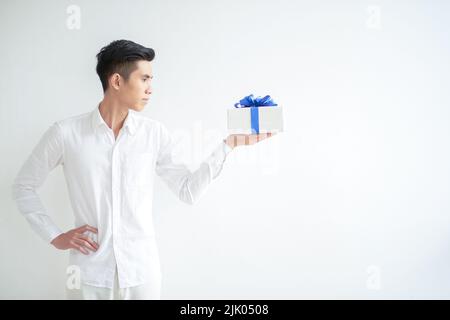 Young Asian man looking at gift on his hand, isolated on white Stock Photo