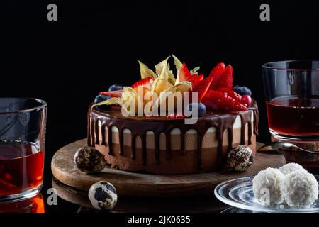 Chocolate cake three chocolate and tea, side view. cake with candies coconut flakes and Chocolate quail eggs. Low key, side view, appetizing cake for Stock Photo