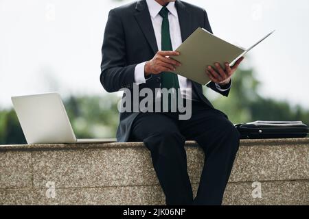 Entrepreneur checking business documents in folder when sitting outdoors Stock Photo