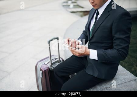 Cropped image of traveling businessman checking messages in his smartphone Stock Photo