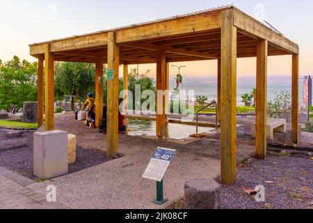 Tiberias, Israel - July 27, 2022: View of a Hot Water wading pool, with bathers, and the Sea of Galilee, in Hamat Tiberias National Park, Northern Isr Stock Photo