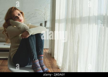 Bored beautiful young woman sitting at the window Stock Photo