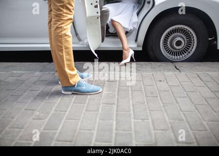 The bride gets out of the car. Stock Photo