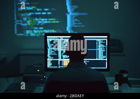 Rear view of programmer working on new project in dark office Stock Photo
