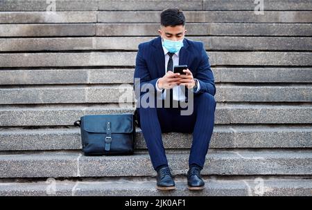 Spending my time missing you. a young businessman sitting on steps using his smartphone. Stock Photo