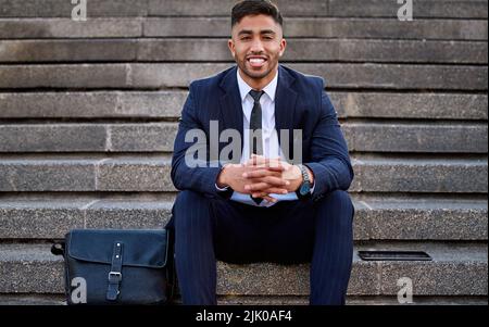 Ive finally reached my dreams. a young businessman enjoying the day sitting on some stairs. Stock Photo