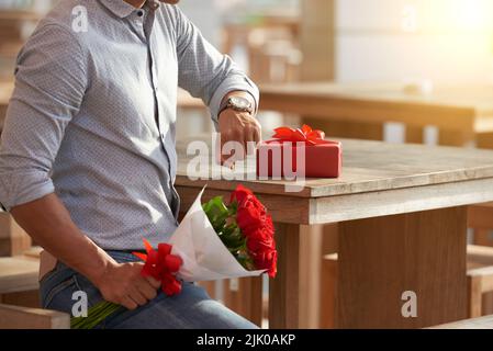 Unrecognizable young man sitting at cafe table and looking at his wristwatch while waiting for his girlfriend, close-up shot Stock Photo