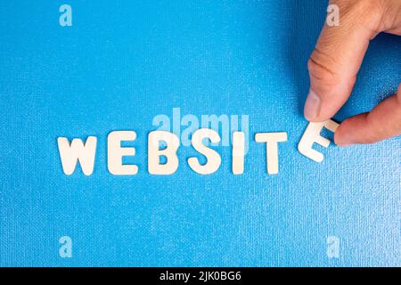 Website. Text from white wooden letters on a blue background. Stock Photo