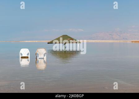 canopy from the sun and two chairs in the water of the dead sea in Israel Stock Photo