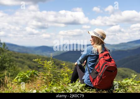stylish traveler woman relaxing in mountains. hipster on top of mountain, resting. space for text. atmospheric moment. wanderlust and travel concept. Stock Photo