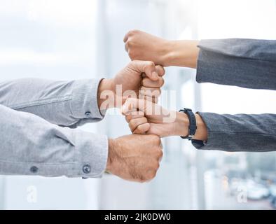 Were all in. two businesspeople stacking their fists on top of each other. Stock Photo