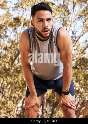 My legs are going to complain tomorrow after this. a handsome young man taking a moment to catch his breath during his outdoor run. Stock Photo