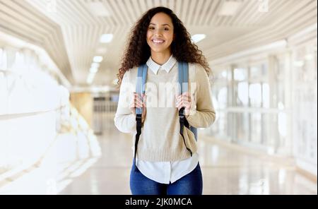 I love learning. Cropped portrait of an attractive young female college student standing with her backing in a campus hallway. Stock Photo