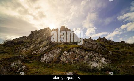 Golden sunrise on the mountain with sun rays coming out from behind the rocks and idyllic atmosphere. La Hiruela Madrid. Stock Photo