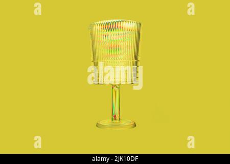 Transparent plastic glass, rainbow colored by photoelasticity isolated on yellow background. Abstract background, frontal view. Environment concept Stock Photo