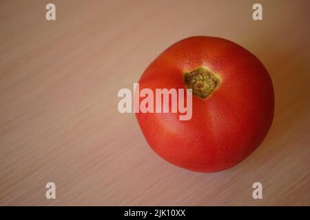 Ripe pink tomato on pale wooden table. Stock Photo