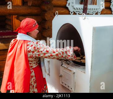 Kazan, Russia. 2022, June 18. A woman cooks traditional flatbread in a Russian stove. The concept of village life. Stock Photo