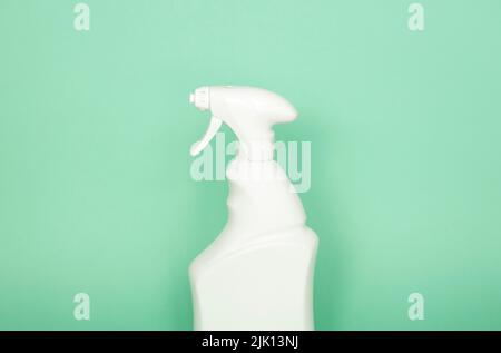 White plastic spray bottle for liquid cleaning products isolated on green background. Packaging mockup bottle with sprayer. Stock Photo