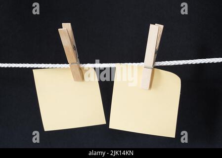 Den Helder, Netherlands. July 2022. Blank memo papers on rope with peg, on black background. Isolated. High quality photo Stock Photo