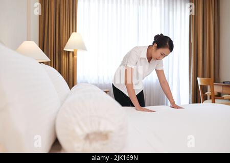 Chambermaid changing linen in the hotel room Stock Photo