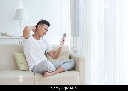 Handsome young man reading messages in his smartphone Stock Photo