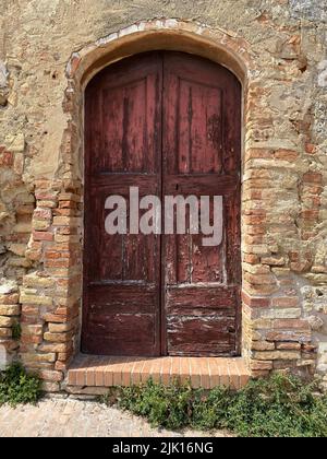 A vertical shot of a vintage arched wooden door of a brick building Stock Photo