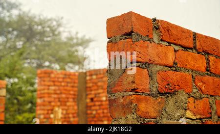 Brick wall under construction on nature background. Red Brick Wall With Diminishing Perspective. Fragment of brown brick wall with a shallow depth of Stock Photo