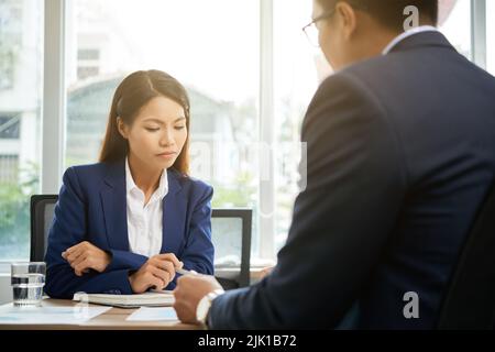 Prety Vietnamese business lady reading agreement carefully before signing it Stock Photo
