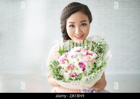 Attractive Asian young woman holding big beautiful bouquet Stock Photo