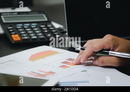 Businessman working in an office with a laptop with data documents graphs and charts marketing research statistics and financial development. Stock Photo