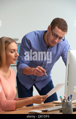 Two coworkers discussing document with financial statistics Stock Photo