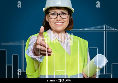 Female industrial worker in hardhat vest extending hand for handshake Stock Photo