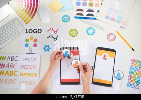 Close-up shot of unrecognizable manager wrapped up in making colorful poster for visual presentation while sitting at office desk Stock Photo
