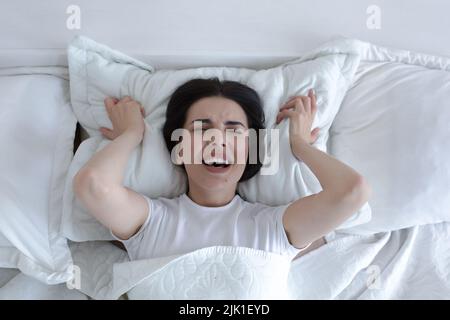 Top view, depressed woman lying in bed crying and screaming with sadness. Stock Photo