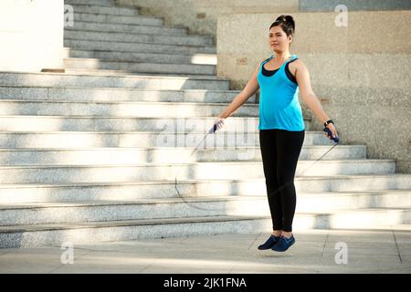 Pretty Vietnamese young woman jumping with skipping rope Stock Photo